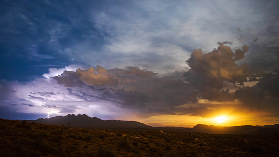 Monsoon lightning and rising supermoon illuminate the night sky above the Four Peaks in Tonto National Forest