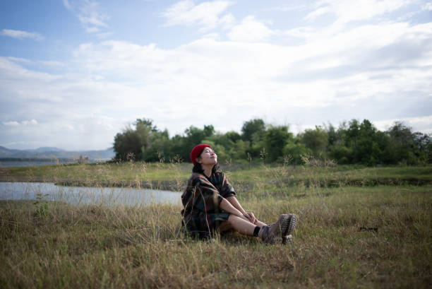 Beautiful woman spending the evening by the river bank in the Nature. ,She looking the beautiful view. Beautiful girl deeply breathing, enjoying relaxation. ,lifestyle concept ,People, lifestyle concept , looking happy , Nature, outdoors
