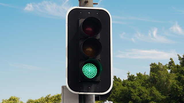 Traffic light changes from red to green against a beautiful clear blue sky