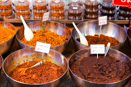 Bowls with different grades of thai chili paste spice on market in Amphawa