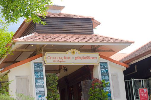 Entrance gate to hotel Chuchai Buri Sri Amphawa at river and waterfront  seen from river level. Around gate are pictures of interior with classical design. Hotel is in outer area of floating market and old town