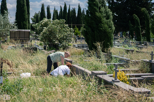 Mother and daughter visit their deceased relatives in the cemetery.