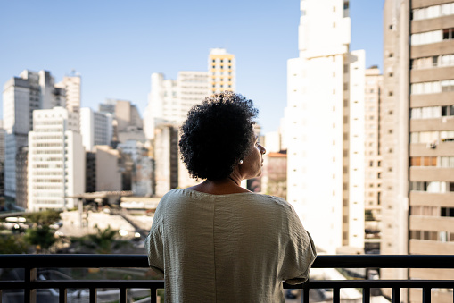 Rear view of a mature woman contemplating on the balcony at apartment
