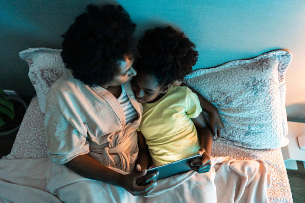 istock Mother kissing her daughter while using digital tablet in the bedroom at home 1655174538