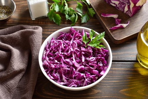 Red cabbage in bowl on wooden table. Close up view