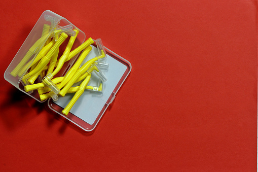 .Image of yellow indental brushes in an open box on a red background in the left corner of the frame.