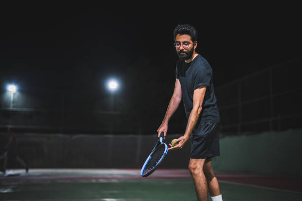 istock Man playing tennis at night 1655355650