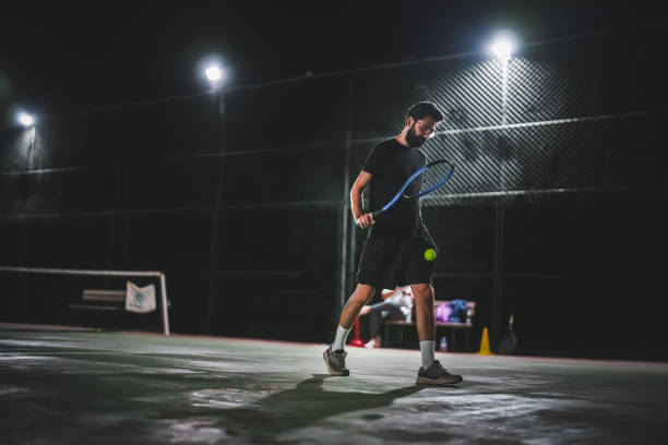 istock Man playing tennis at night 1655365876