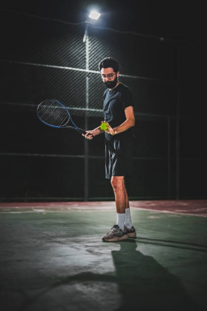 istock Man playing tennis at night 1655365879
