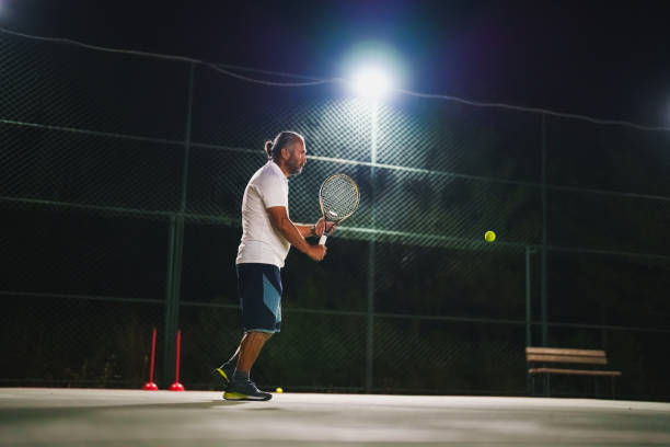 istock Man playing tennis at night 1655382575