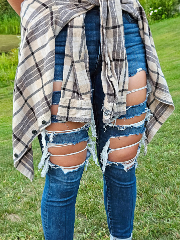 Teen girl wearing a tied flannel shirt over ripped jeans