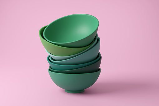 Randomly stacked green shaded bowls on pink background with shadow in monochrome and minimalism. Illustration of the concept of home cooking, dinner and culinary