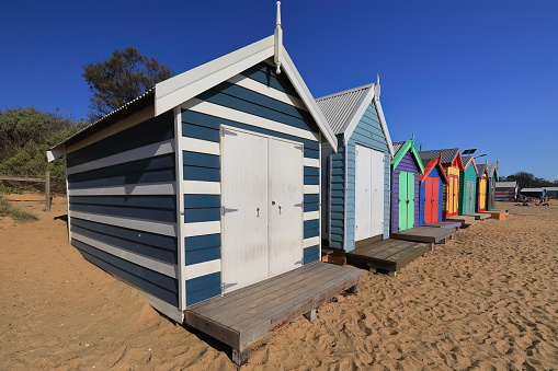 Several of the 82 colorful Victorian bathing boxes along Dendy Street Beach, timber structures facing W.to Port Phillip Bay seen in the late afternoon, Brighton Beach Suburb. Melbourne-VIC-Australia.