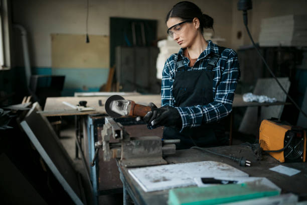 istock Young woman working with angle grinder machine in metal workshop 1655561499