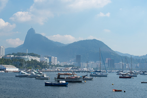 Rio de Janeiro, Brazil: Urca district, view of Guanabara Bay and the harbour for fishing boats with misty city ​​skyline and Christ the Redeemer on Corcovado Mountain on the background