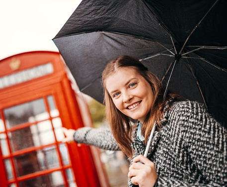 Teenage Girl Sheltering From Rain Beneath Umbrella Smiling