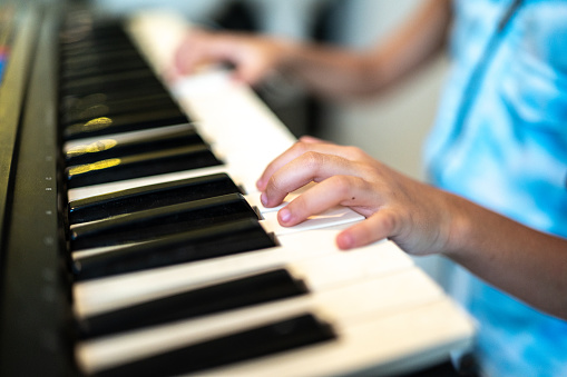 Close-up of a child hand playing a digital piano keyboard