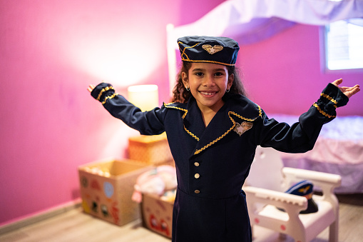 Portrait of a child girl playing at being a flight attendant in the bedroom at home