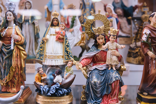 Souvenirs religiosos de pequeñas estatuas de vígenes, santos y Cristos expuestos en una vitrina