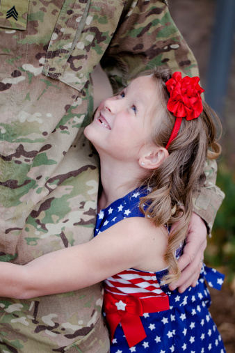 Daughrer holding on and looking up at her father, a U.S. Army Soldier.