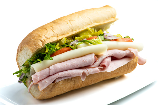 Sliced ham, Cheese, lettuce and tomato submarine sandwich on white background