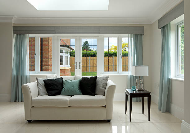 settee and side table a simple composition of a settee with side table set in a luxury new home. Black silk cushions on the settee complement the dark wood table whilst the  light turquoise cushion and the glass bowl on the table match the curtains. The settee is a light cream colour and sits on a light marble floor.  architectural cornice stock pictures, royalty-free photos & images