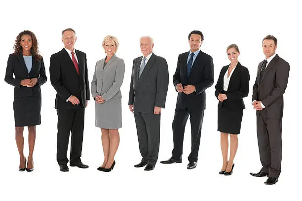 Business people of various ethnicity and age stand in a row and smile at the camera. Horizontal shot. Isolated on white.