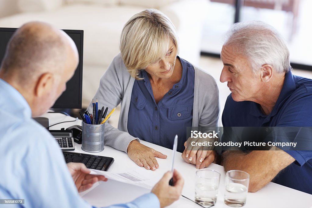 Senior couple looking at each other before signing the document Senior couple looking at each other before signing the document at the financial consultant office 50-59 Years Stock Photo