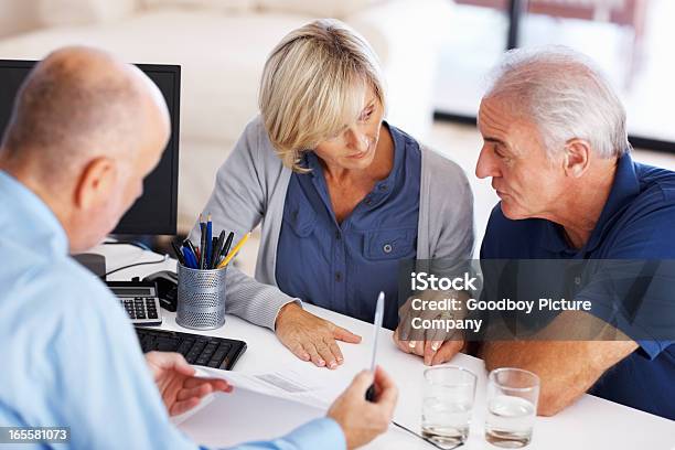 Senior Couple Looking At Each Other Before Signing The Document Stock Photo - Download Image Now