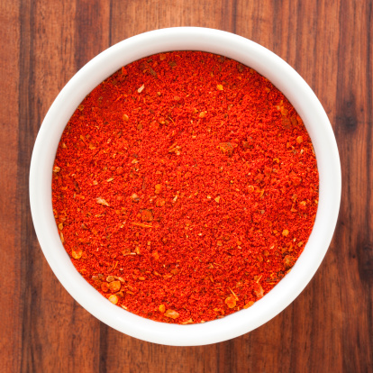 Heap of paprika with sweet bell peppers on light grey table, closeup