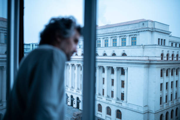 Urban lifestyle. Man looks from tall building window. Off-season travel on a city break. bucharest people stock pictures, royalty-free photos & images