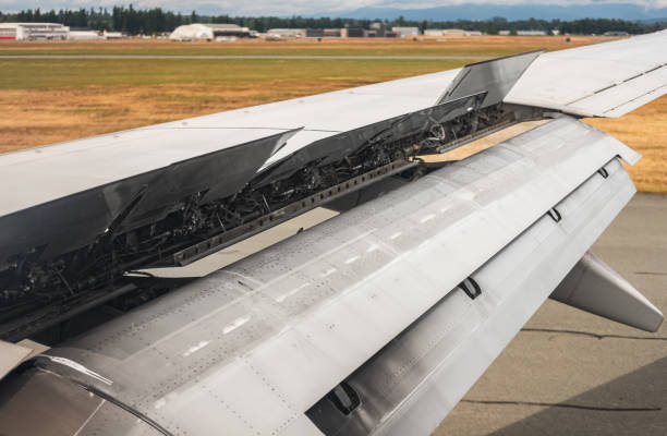 Landing airplane. An airplane window view of wing and flaps after landing. Airplane wing with the spoiler open Landing airplane. An airplane window view of wing and flaps after landing. Airplane wing with the spoiler open. Travel photo, nobody upward mobility stock pictures, royalty-free photos & images