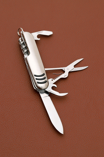 Close up photo of swiss army knife on brown leather background