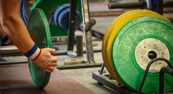 A weightlifter prepares weights for his barbell.