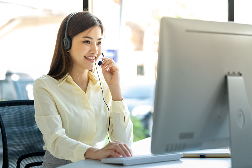 Call center, woman and working in team office with headset, computer and online customer support, service or help. Businesswoman, smile and contact us, crm and telemarketing employee talking