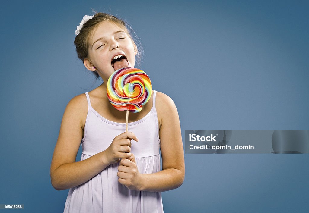 Felice, giovane 9 anni vecchio ragazza con Lecca-lecca in blu - Foto stock royalty-free di Bambine femmine