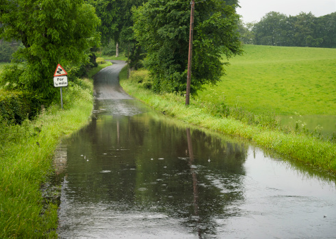Standing water on a rural road during heavy rain.