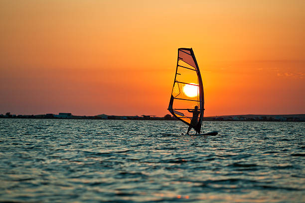 windsurfingu na zachód słońca - windsurfing zdjęcia i obrazy z banku zdjęć