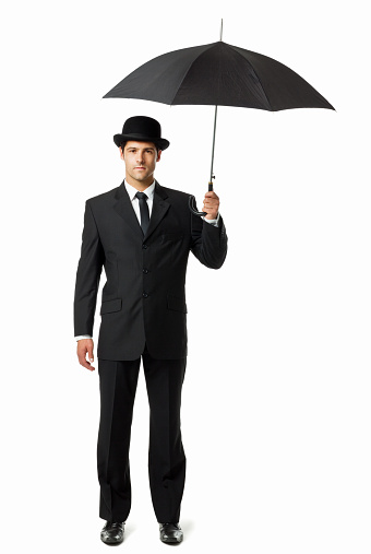 Well dressed man in a bowler hat, holding an umbrella overhead. Vertical shot. Isolated on white.