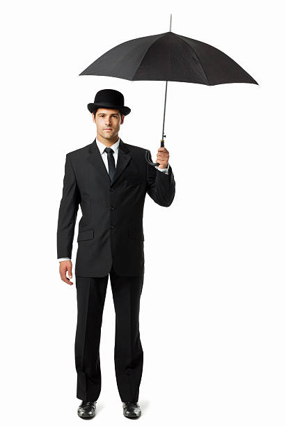 Gentleman Holding an Umbrella - Isolated Well dressed man in a bowler hat, holding an umbrella overhead. Vertical shot. Isolated on white. bowler hat stock pictures, royalty-free photos & images