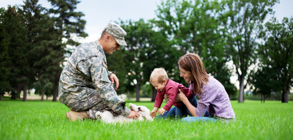 Real American Soldier With Wife & Son playing with their dog in the park. 