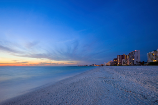 Row of resorts, hotels on white sandy beach at sunset