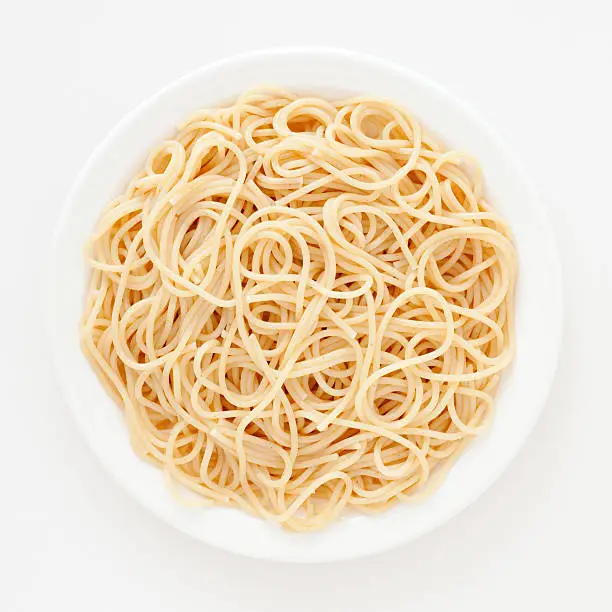 Top view of white dish with boiled spaghetti over it