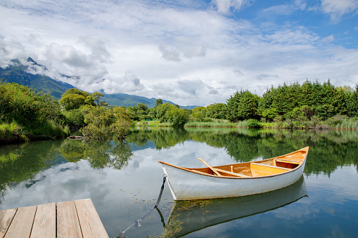 A lone canoe sits on shore on a peaceful lake at sunset. The odd colored clouds in the background are from a forest  in Lijiang, China in the summer of 2023.