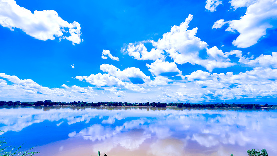 Blue sky scenery with lake on foreground and reflection in water with landscape of a calm lake