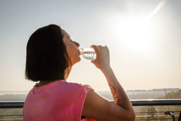istock Dark-haired lady stands facing sun and swallows water 1656242113
