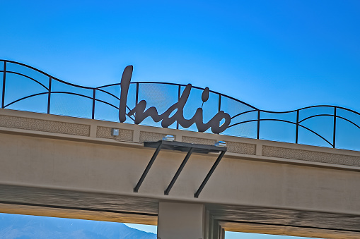 A city sign on a freeway overpass lets travelers know they are in Indio California.