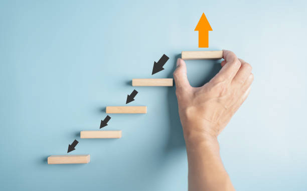 istock Hand holding wooden block orange arrow and different direction facing opposite direction with black arrow for business disruption and technology transformation and different thinking idea 1656300634
