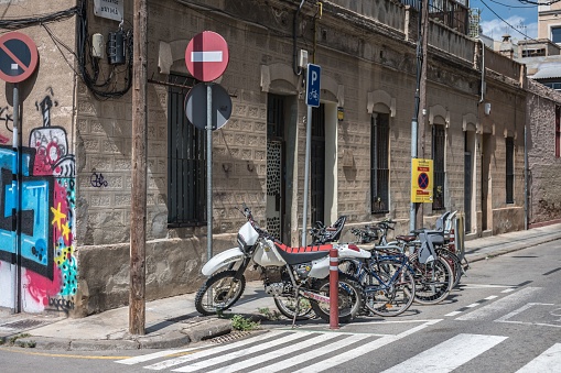 Barcelona, Spain – August 12, 2023: An old corner of the city of Barcelona with parked two-wheelers, old town with traffic signs