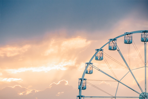 Ferris wheel spinning in a cloudy summer evening sky